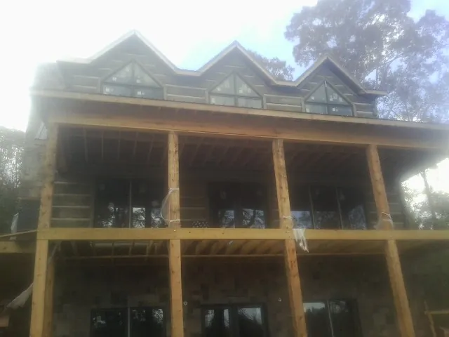 Dormers and porch framing on a large log home under construction — Roof Coating work by our crew in Goshen