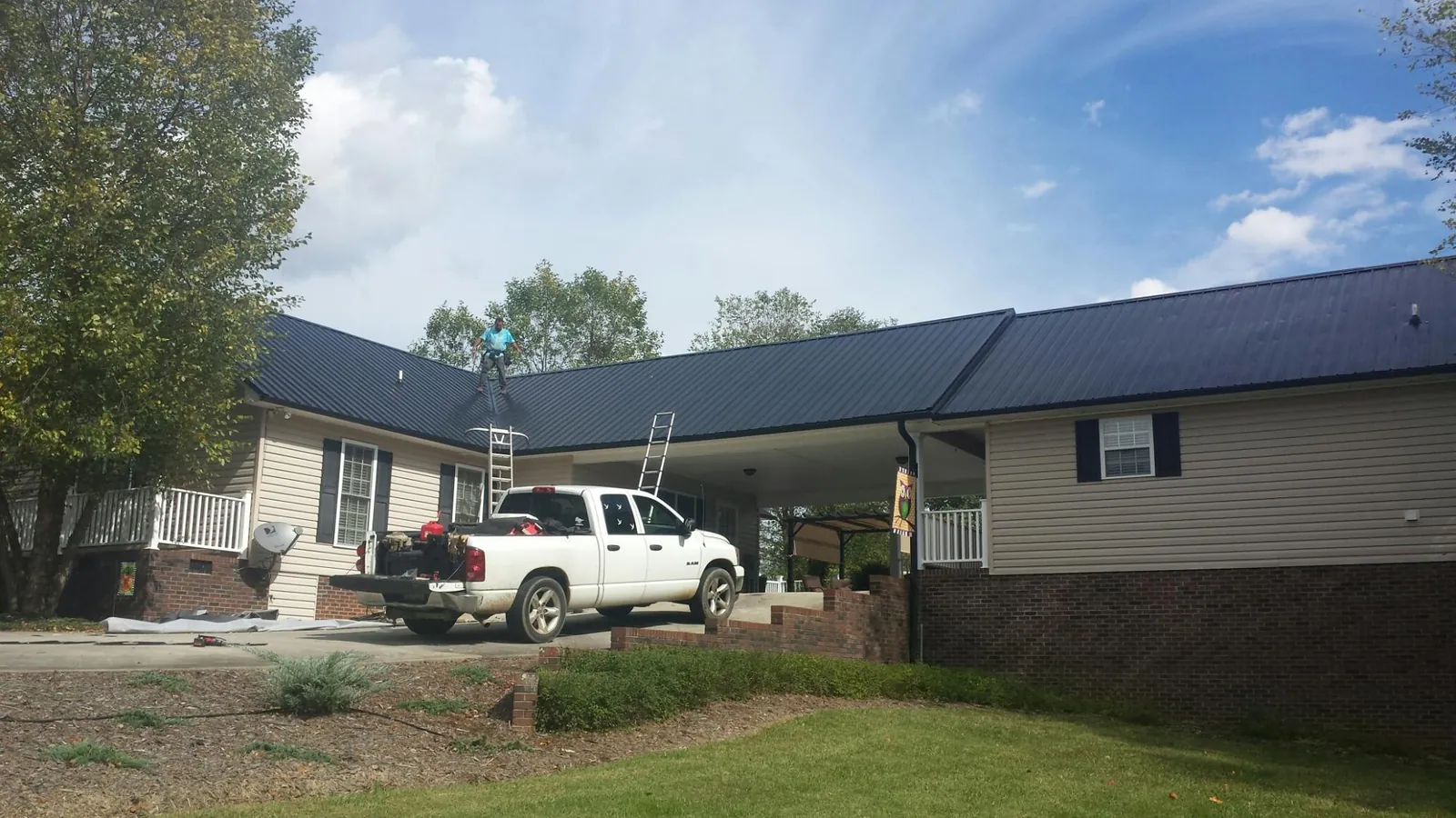 Black metal roof over a home and attached breezeway with ladders set in Goshen