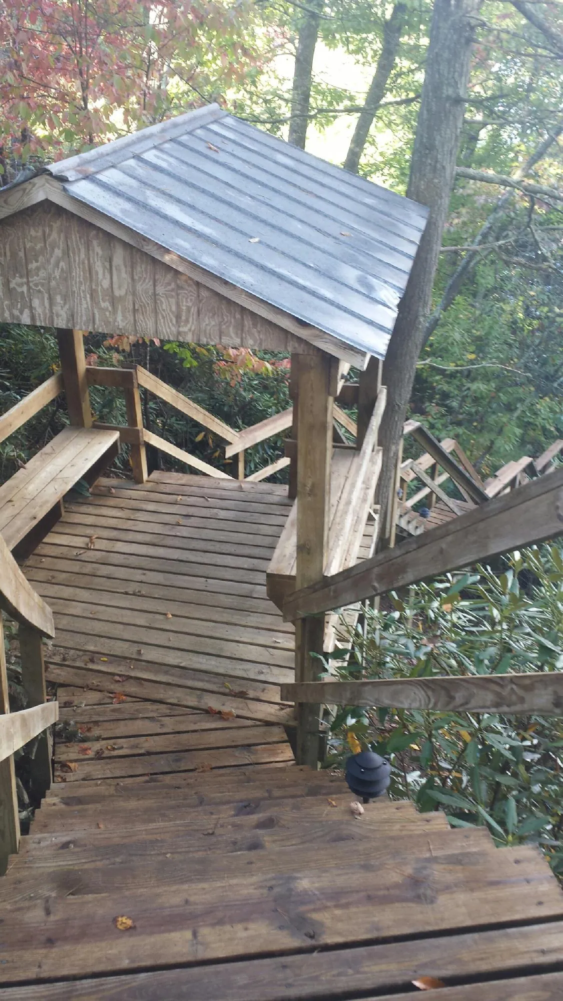 Metal roofed shelter over wooden steps on a wooded walkway — Skylight Repair & Installation work by our crew in Goshen
